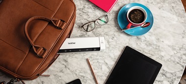 top down view of desk with; brother mobile printer, coffee and a tablet